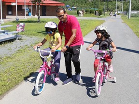 Raihan Patwary helps his daughters, Namira, 7, left, and Noura, 5, learn to ride their bikes in Sudbury, Ont. on Friday July 17, 2020.
