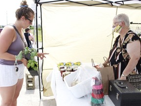 Carolyn Gummer, left, inquires about some of the preserves on display with one of the vendors Arma Kirkman, during the first day of the Mountjoy Farmers' Market held this past Saturday at the Participark in the city's west end.  

RICHA BHOSALE/The Daily Press