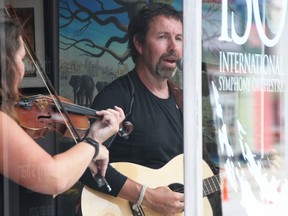 Jim Lahey performs with ISO violinist Caitlin Mason behind glass at the International Symphony Orchestra's downtown Sarnia office Aug. 1. Regular 2 p.m. Saturday concerts are planned until the end of September as part of an every-weekend, pedestrian-friendly street pilot project. (Tyler Kula/The Observer)