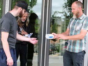 Indwell regional manager Justin DeWaard, right, provides two residents - Sean and Michael - with phones to help them better connect to services during the pandemic. The Refuge, Domestic Abuse Services Oxford, Wellkin and Indwell will receive a combined $201,000 from a fund with the Oxford Community Foundation. (Submitted photo)