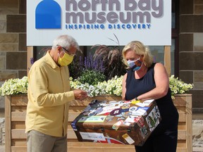 Nipissing MPP Vic Fedeli places a City of North Bay sticker on the travelling suitcase held by Lisa MacLeod, Minister of Heritage, Sport, Tourism and Culture Industries Tuesday at the Discovery North Bay Museum. MacLeod announced Tuesday morning more than $690,000 toward festivals, and art and tourism sectors.