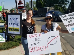 Sarah Dudgeon, left, and Rachel Presley, co-organizers of a protest asking council to revisit the mandatory indoor mask bylaw, are shown at the corner of King Street West and Third Street in Chatham on Saturday. (Trevor Terfloth/The Daily News)