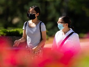 Two women wear masks to protect themselves from COVID-19 at Coronation Park in Edmonton, on Sunday, Aug. 23, 2020.