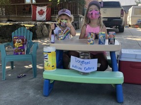 The Stubbs sisters raised $250 last weekend with their Saturday morning snack stand, with all proceeds going to Autism Ontario – and organization the family chose after Zoey's autism diagnosis last spring. Picture, Zoey (right, age 5) and Quinn (left, age 3) with snacks, masks and a donation on Saturday. (Courtesy Alisha Stubbs)