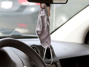 A mask hangs from a mirror in a vehicle in Stony Plain Monday. Council in the town had a special meeting that day where it was found that residents who responded to a survey on mandatory mask use were about evenly divided and a debate on a bylaw is set for the start of next week.
