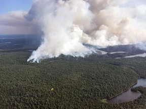 A Ministry of Natural Resources and Forestry water bomber in the foreground is dwarfed by a large plume of smoke behind it as fire crews continued to battle forest fires in the Temagami region in July 2018. A new study suggests extinguishing forest fires as they’re reported may not be the best choice for nearby communities. FILE PHOTO/POSTMEDIA NETWORK