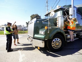 A New Wave Activist is issued a 'disobey red light' under the Highway Traffic Act section 144-25 for holding up a livestock transport who had the right-of-way at the entrance of Sofina Fearmans Pork, Inc. processing facility in Burlington while an Agriculture Strong: Truckers and Farmers Fed Cities supporter gives hotdog to the driver Aug 20. (Diana Martin, Ontario Farmer)