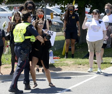 Sabrina Desgagne, New Wave Activist, is removed from the entrance of Sofina Fearmans Pork Inc. by Halton Regional Police Service Const. Barnes as she attempts to step in front of a moving livestock transport as it makes its way into the processing plant Aug. 20 Diana Martin, Ontario Farmer