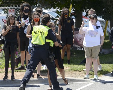 Sabrina Desgagne, New Wave Activist, is removed from the entrance of Sofina Fearmans Pork Inc. by Halton Regional Police Service Const. Barnes as she attempts to step in front of a moving livestock transport as it makes its way into the processing plant Aug. 20