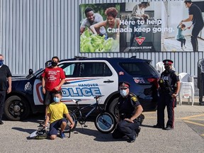 From left to right, Cathy Cousins, Dale Cousins, Dane McMurray, Jose, Hanover Police Chief Chris Knoll and Constable Crystal Lavigne pose for a photo as Jose  is presented with new bike, helmet and lock in front of Hanover's Canadian Tire after his was stolen. Photo supplied.