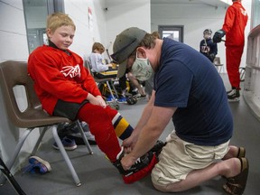 Andrew Farrow ties the skates of his son Carter, 9, at the Western Fair Sports Centre in London on Friday July 31, 2020. Carter was participating in a Total Package Hockey skills camp. Camps are limited to 12 players and three instructors because of COVID-19. (Derek Ruttan/The London Free Press)