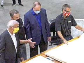 Columbia Forest Products woodlands and fibre resources manager Dan Bowes, second from left, explains the veneer process at the plant to Nipissing MPP Vic Fedeli and Ontario Minister of Natural Resources and Forestry John Yakabuski, while plant manager Chris Daur operates the machinery on Thursday, Aug. 27, 2020. (PJ Wilson/Postmedia Network)