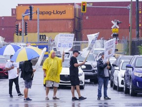 Striking Port of Montreal workers brave the elements to walk the picket line in Montreal on Monday, August 17, 2020. The gradual return to work of 1,125 longshore workers at the Port of Montreal's began Sunday allowing activities to resume after a 12-day strike. On Friday, the union representing dock workers and the employer announced they'd reached a truce, putting an end to a labour action that began Aug. 10, leaving thousands of containers untouched on the docks. (THE CANADIAN PRESS/Paul Chiasson)