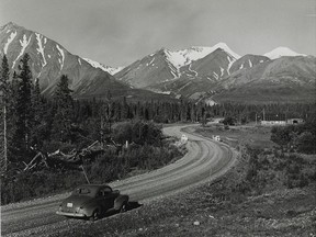 Mile 1,021 of the Alaska Highway, with the snowy peak of Mt. Archibald shining ahead in 1949, near Bear Creek, Yukon. (Richard Harrington/Department of Indian Affairs and Northern Development/Library and Archives Canada)