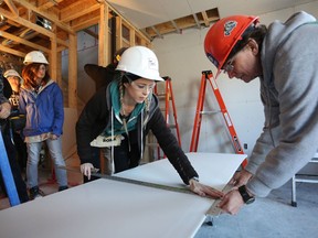 Teri Buffett and Deb Wilson measure and cut drywall at the Habitat for Humanity building site on Cowdy Street in downtown Kingston on March 14.