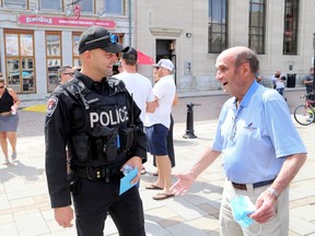 Kingston Police Const. Fil Wisniak chats with recovered stabbing victim Terry Stafford before Wisniak received the Police Association of Ontario 2020 Police Hero On-Duty Difference Maker (Uniform/Sworn) Award on Monday for his response to a stabbing in downtown Kingston last year. (Ian MacAlpine/The Whig-Standard)