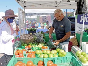 Wayne Chalmers fills a bag with produce for customer Marianne Rogers at the North Bay Farmers' Market, Wednesday.
PJ Wilson/The Nugget