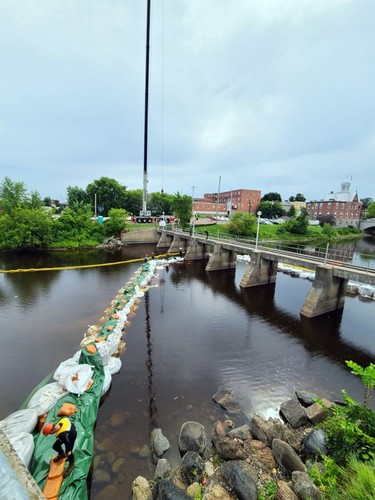 A crane was used to place large bags containing stones in the Muskrat River near Pembroke city hall to create a temporary dam that is required as part of the dewatering and demolition process to remove the Muskrat River dam.