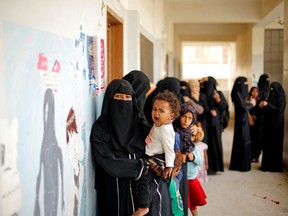 A woman from the Muhamasheen (marginalized) community carries a child as they wait at a charity clinic near their neighbourhood in Sanaa, Yemen, on July 9. (Khaled Abdullah/Reuters)