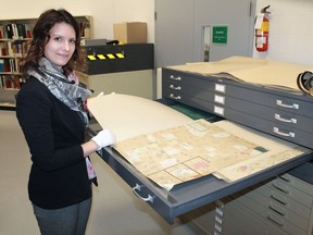 Archivist Nicole Aszalos studies an old county map in the Lambton County Archives vault in Wyoming. The Lambton County Archives is seeking people's personal stories about pandemic life amid COVID-19. (File photo)