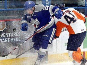 Sudbury Wolves defenceman Jack Thompson (22) shrugs off a hit from Flint Firebirds forward Evan Vierling (41) while clearing a puck along the boards during first-period OHL action at Sudbury Community Arena in Sudbury, Ontario on Friday, February 8, 2019. Ben Leeson/The Sudbury Star/Postmedia Network