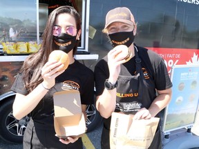 Brand ambassador Jessica Monteiro, left, and HaRVey's RV Tour activation lead Kat Johnstone display a couple of Harvey's hamburgers beside the HaRVey's RV, which stopped outside the RioCan Centre in Sudbury on Wednesday to hand out free thank-you burgers as a show of appreciation for front-line grocery store workers, as part of a cross-country tour that will see the company hand out some 50,000 burgers. Ben Leeson/The Sudbury Star/Postmedia Network