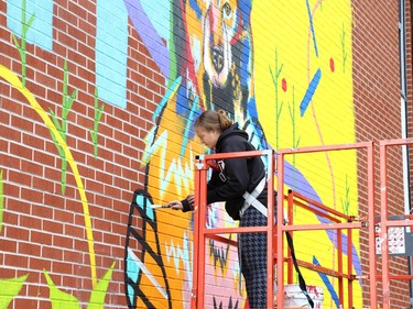Artist Ashley Guenette works on her mural for Up Here, Sudbury's urban art and music festival, at Minnow Lake Place on Bancroft Drive in Sudbury, Ont. on Tuesday August 18, 2020. The sixth edition of the festival has been reimagined because of the pandemic, and will include the creation of five new large-scale murals by five local artists. John Lappa/Sudbury Star/Postmedia Network