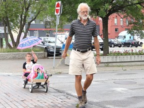 Kyree Zinger, 5, attempts to keep dry while travelling with her grandfather, Albert Sieve, in downtown Sudbury, Ont.