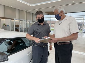 James Toyota sales representative Bob Larose, left, and Timmins Chamber president Val Venneri, who is also the car dealership's general manager, conduct business while wearing their masks inside the building in July. The public is required to wear a mask or face covering when entering indoor public spaces in Timmins and the Town of Stony Plain is now debating a similar proposal like the City of Spruce Grove.