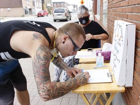 Justin Nenonen signs a petition in support of a grocery store being re-established at the Porcupine Mall as Brenda Torresan, the petition organizer, looks on. Signatures were being collected outside the LCBO in South Porcupine on Saturday. Metro, which owns the Porcupine Mall, closed the only grocery store in the city's East End a year ago. Torresan said the petition is also available online until Aug. 15 and urged supporters to add their name by searching for Petition for Porcupine Mall Grocery Store on Facebook. 

RICHA BHOSALE/The Daily Press