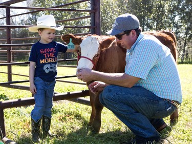Aaron Dennison, left, tells little cowboy Easton Moore about his cow Molly. Dennison and Molly were at Blue Ridge Farms Sunday as part of the Alberta Open Farm Days. 
Brigette Moore