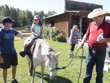 Barry Farnsworth, left, helped his five-year-old daughter Emmy up on the horse for a ride at Blue Ridge Farms. Barry Trebilcrck lead the horse around the yard. 
Brigette Moore