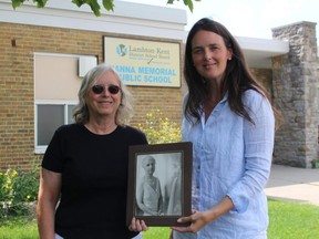 Sandi Spaulding, left, and her daughter Carly Erickson hold a photo of their ancestor Maude Hanna outside the Sarnia school named in her honour.