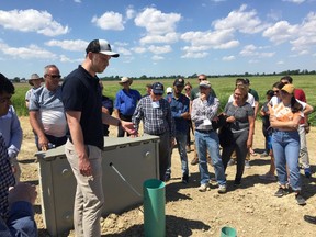 Colin Little, front, from the Lower Thames Valley Conservation Authority, explains how the phosphorus capturing water tank at the Roesch farm works to a group of people on June 26, 2019. (Jake Romphf, Postmedia Network)