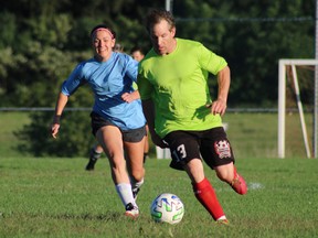 Jason Lingard defends the ball against Sadie Boyd on Friday night during an adult recreational soccer league at the Norfolk County Youth Soccer Park. Blue team won the game 4-0. (ASHLEY TAYLOR)