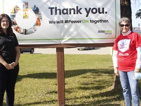 Kate Cantin, left, stakeholder relations officer, with Ontario Power Generation in Timmins, and Sharon Montreuil, facilitator for the Timmins Parkinson’s Support Group, check out an OPG billboard. OPG donated $1,000 to help support the organization that works with people suffering from the disease. RICHA BHOSALE/THE DAILY PRESS