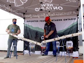 New Ontario Brewing Co. president and brewmaster Mike Harrison, centre, marks the grand opening of the brewery’s new location on Seymour Street, Saturday, with a different take on the traditional ribbon cutting — a chainsaw and birch tree. Michael Lee/The Nugget