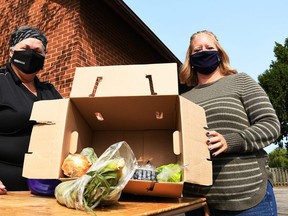 Dava Robichaud, events coordinator with TekSavvy, left, and Lyndsay Davidson, registered dietician with CK Public Health, display one of the boxes of fresh produce given away as part of the Mobile Miracle Market at Wheatley Baptist Church Sept. 15, 2020. (Tom Morrison/Chatham This Week)