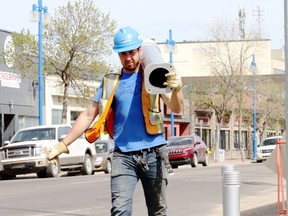 Morgan Wilcox, with Wapiti Gravel, removes a barrier on 100 Avenue to start construction on the street, on Monday May 14, 2018 in Grande Prairie, Alta.