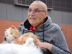 Bruno Sagmeister holds a lifelike robotic cat named Sweetie Pie in his lap in front of Mackenzie Place Continuing Care Centre in Grande Prairie, Alta. on Wednesday, Sept. 23, 2020. Sagmeister is showing an improvement in his dementia as a result of recently adopting the imitation feline.