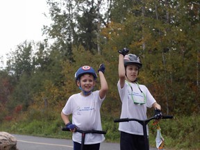 Ten-year-old Vincent Pardy, right, and his brother Edward Pardy, 7, celebrate, Sunday afternoon, on Cranberry Road after spending several months scootering the Kate Pace Way and Kinsmen Trail. Michael Lee/The Nugget