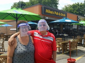 Donning protective equipment, Brenda and Mike Buckler, co-owners of Mike's Place in Chatham, are shown outside the patio of their establishment in June. (Trevor Terfloth/Postmedia Network)