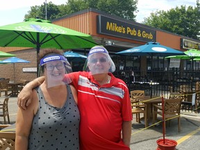 Donning protective equipment, Brenda and Mike Buckler, co-owners of Mike's Place in Chatham, are shown outside the patio of their establishment in June. Trevor Terfloth/Postmedia Network