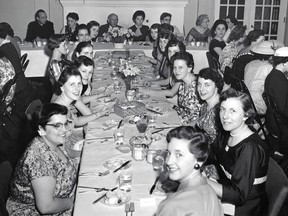 Graduation Banquet of the Class of 1957 of St Joseph's Hospital School of Nursing. From top of left side of centre table, counter-clockwise to top of right side of centre table: Nancy Danyk, Joyce Craig, Patricia MacKenzie, Audrey Leach, Anne Savin, Betty Lachine, Margaret Thomas, Elaine Godin, Leona Amerlinck, Norma Garbutt, Helen Daigneault, Mary Ann Gartner, Marlene Skinner, Johanna Burgess (head turned to the next table) and Nancy Lawson. Just left of the centre of the head table, wearing glasses: Dr. Fred Reid (surgeon; Class of 1906, University of Western Ontario Medical School). At the top of the left side of the table to the right of the centre table and facing the camera: Dina Marini (graduate of the Class of 1947 of the St Joseph's Hospital School of Nursing). Photo taken sometime not long before May 5, 1957 at the Glen Gordon Manor, Cedar Springs. Photographer unknown; submitted by Helen Martinello.