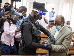 Paul Rusesabagina, right, is handcuffed by a police officer after his pre-trial court session at the Kicukiro Primary court in Kigali, Rwanda, on Sept. 14.