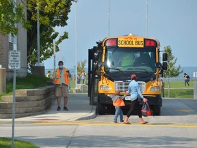 A parent picks up a child as school buses line up at Ecole East Ridge Community School in Owen Sound.