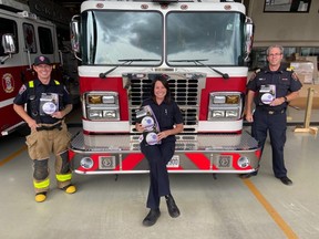 Firefighter Eric Smith, left, public educator Whitney Burk and assistant chief Ken Labonte of Chatham-Kent Fire & Emergency Services show the smoke and carbon monoxide alarms provided to homes through the Project Zero public education campaign. (Chatham-Kent Fire & Emergency Services photo)