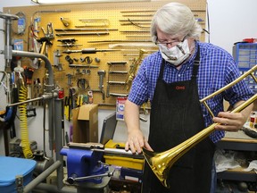 Using a steel rod in a vise, Greg Hendrickson rolls a dent out of a trombone's bell.