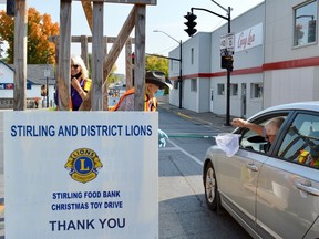 Stirling Lions club member, Lin Clarke, pictured here, extending a butterfly net, accepts a cash donation from a passing motorist as Lion, Tina DeVries, adjusts her protective mask. The eighth annual Toll Booth fundraiser was held at the four corners in the village last Saturday and raised $4,453 in support of the local food bank and Christmas Toy Drive.
TERRY VOLLUM