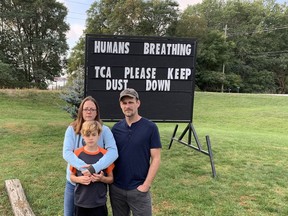 Stephanie and Robert Slack and their son, Oliver, stand near a sign they put up on their Oakhill Drive home. The family says dust from an aggregate pit on Colborne Street West across from their home is causing problems.